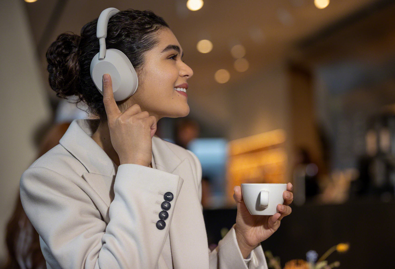 Naine kandmas Sony XM5 kõrvaklappe kohvikus