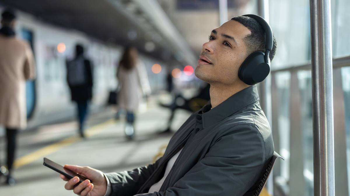 Mees kandmas Sony XM5 kõrvaklappe raudteejaamas