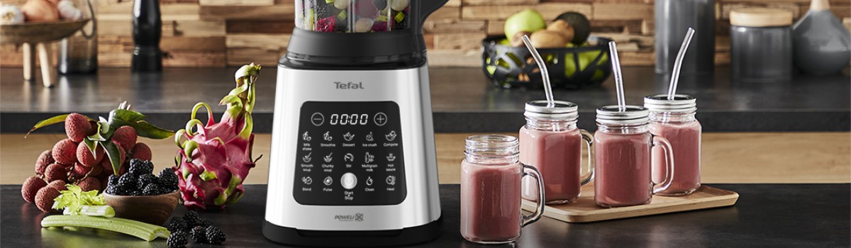 Суперблендер Tefal Perfectmix Cook на кухонной поверхности с свежими ягодами и четырьмя стаканами для смузи
