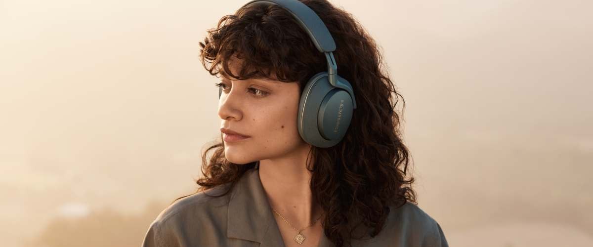 Naine kannab siniseid Bowers &Wilkins juhtmevabasid kõrvaklappe ja vaatab küljele