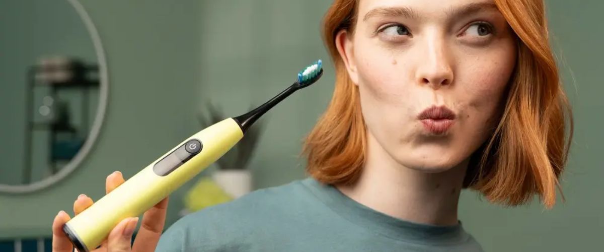 Naine hoiab käes kollast Beureri elektrilist hambaharja