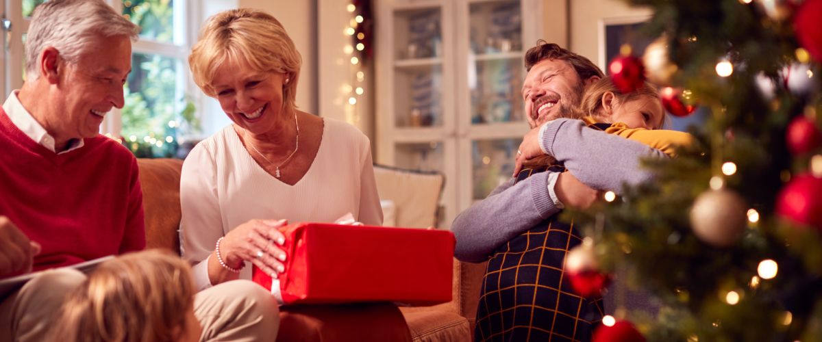 Семья открывает упакованный рождественский подарок для родителей