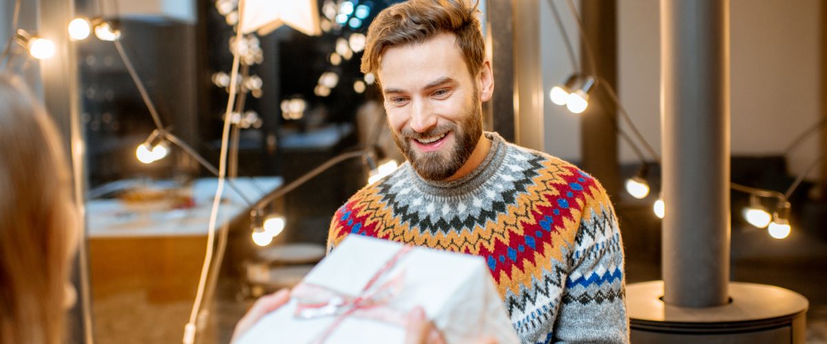 Улыбающийся мужчина получает упакованный рождественский подарок для мужчины