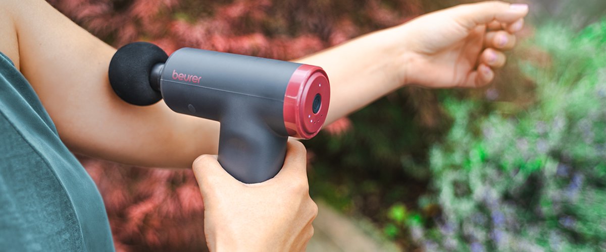 Naine hoiab käes Beureri massaažipüstolit lihaste lõõgastamiseks