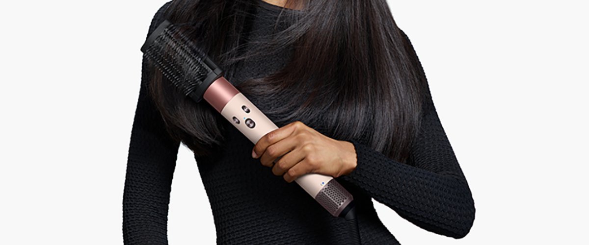 женщина в черном платье держит в руках стайлер Dyson Airwrap