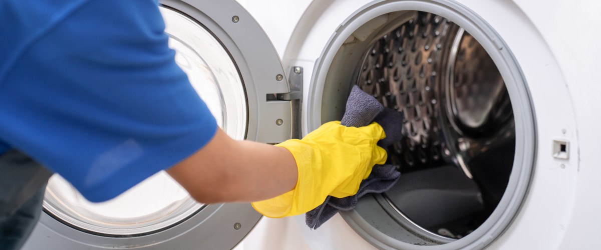 На переднем плане рука чистит духовку губкой и чистящим средством