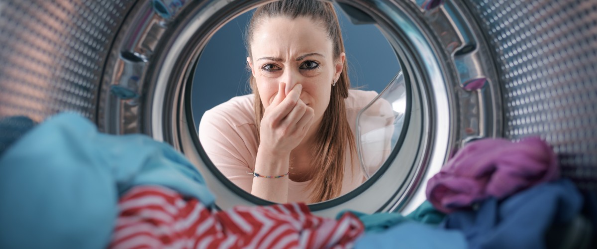 Naine vaatab pesumasina trumlit otsides põhjuseid ebameeldivatele lõhnadele
